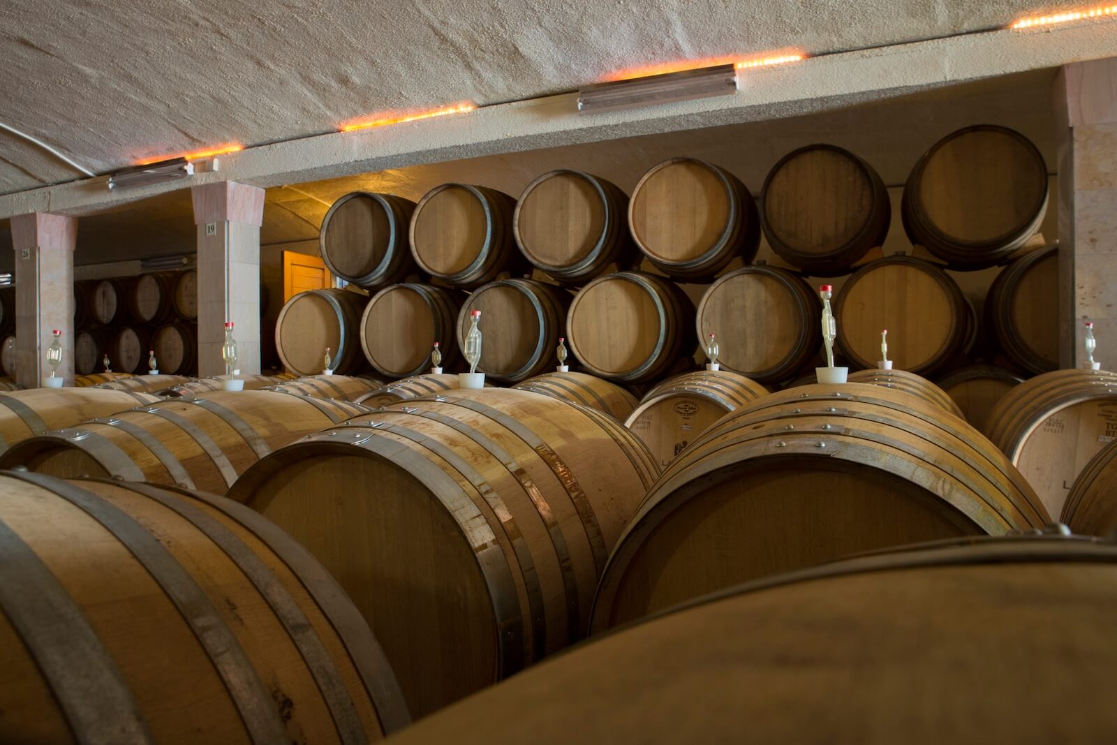 Inside the Lanzerac barrel maturation cellar, showing rows of traditional oak barrels used for ageing wine.